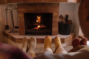 Row of socked feet in front of a fireplace functioning safely after Monmouth County chimney service