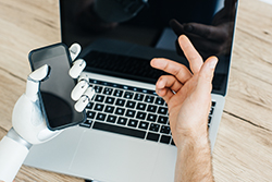 Ocean County SEO and AI - 1 human hand over a laptop and 1 robotic hand holding a cell phone